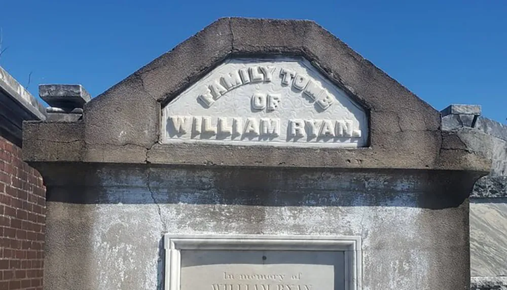 The image features the weathered stone facade of a mausoleum with the inscription FAMILY TOMB OF WILLIAM RYAN at the top