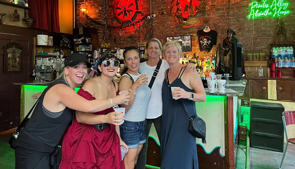 Five smiling people pose with drinks inside a bar decorated with pirate-themed decor