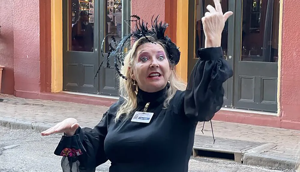 A woman in black attire with feathery head decoration appears to be entertaining or performing making an expressive hand gesture and a surprised facial expression