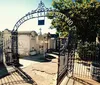 The image shows the ornate entrance gate to Lafayette Cemetery No 1 surrounded by aged crypts under a clear sky