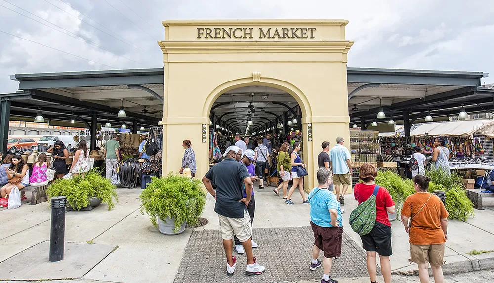 Visitors browse through various stalls under a long covered market with an archway labeled FRENCH MARKET