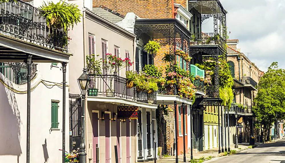 This image shows a picturesque street in the French Quarter of New Orleans lined with historic buildings featuring colorful facades and ornate ironwork balconies some adorned with plants