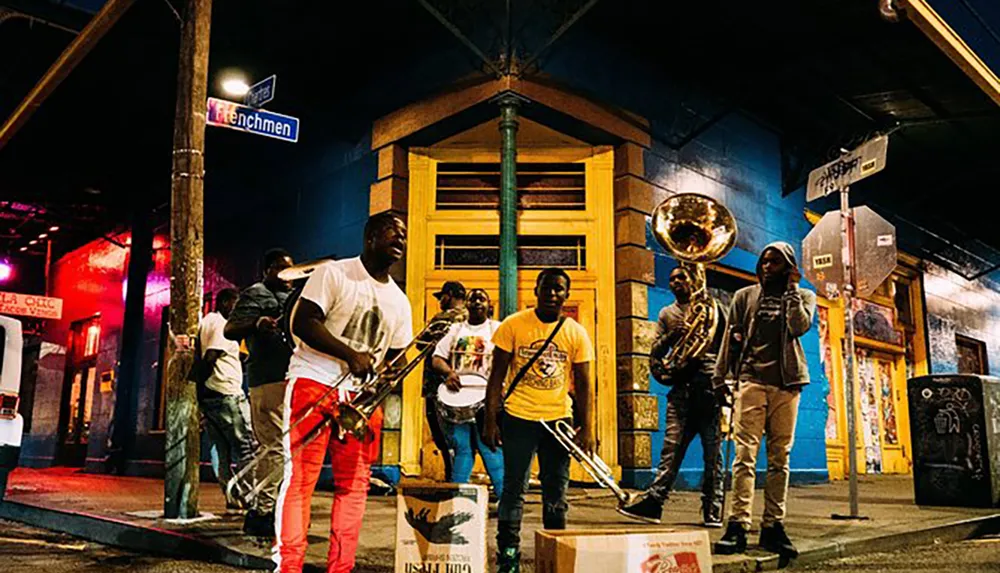 A group of musicians is performing on a vibrant street corner at night adding a lively ambiance to the urban setting