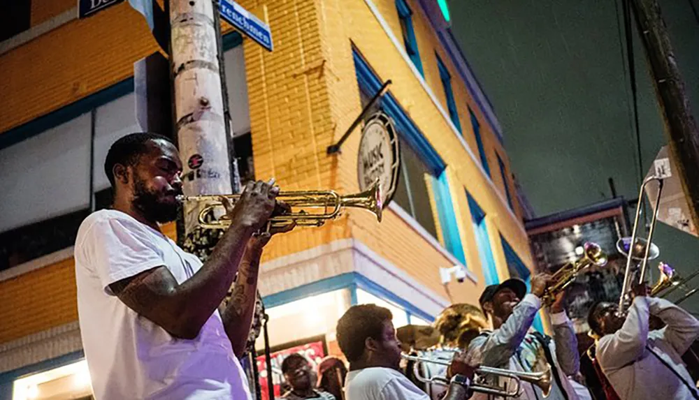 A group of musicians prominently featuring a trumpet player is performing on a vibrant city street at night
