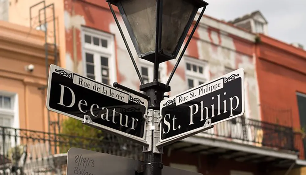 The image shows a street lamp post at the intersection of Decatur Street and St Philip Street with additional signage indicating Rue de la Levee and Rue St Philippe set against the backdrop of historic buildings possibly in New Orleans