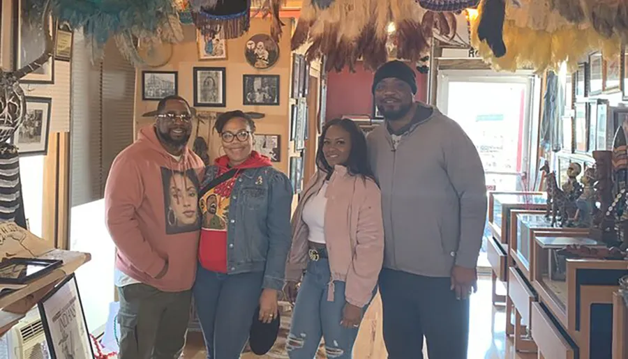 Four people are smiling for a photo inside a room with eclectic decor and artifacts.