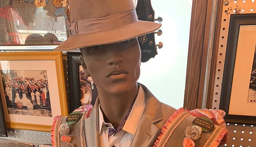 A mannequin displaying a wardrobe with a beige hat suit and necktie holding two colorful bridal bouquets