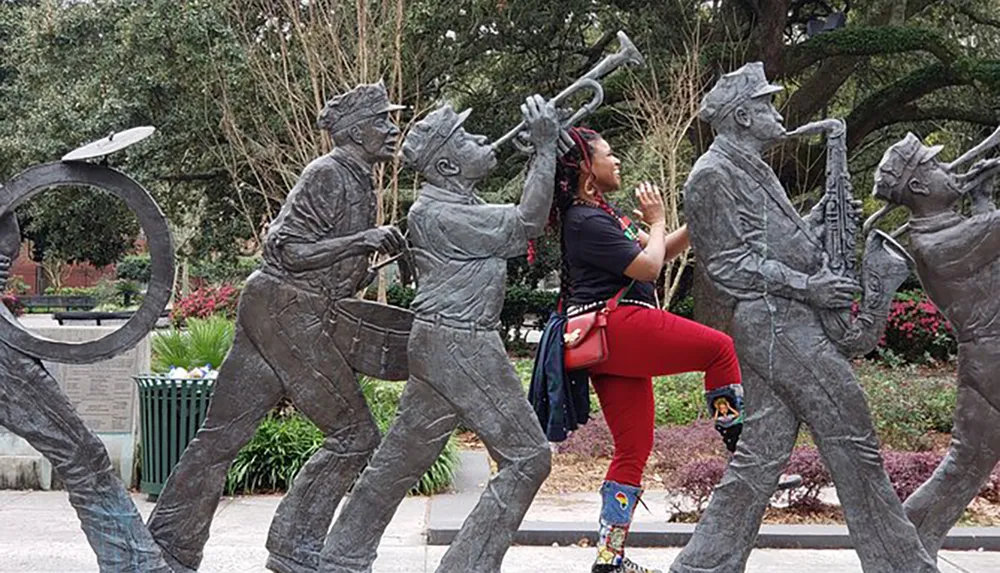 A person is playfully interacting with a sculpture of a jazz band by pretending to sing along with the musicians