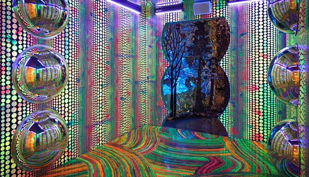 The image displays a vibrant psychedelic room adorned with a multitude of colors patterns and reflective disco balls creating a visually stimulating environment