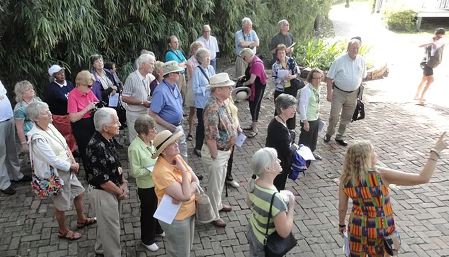 A group of adults attentively listening to a tour guide outdoors.