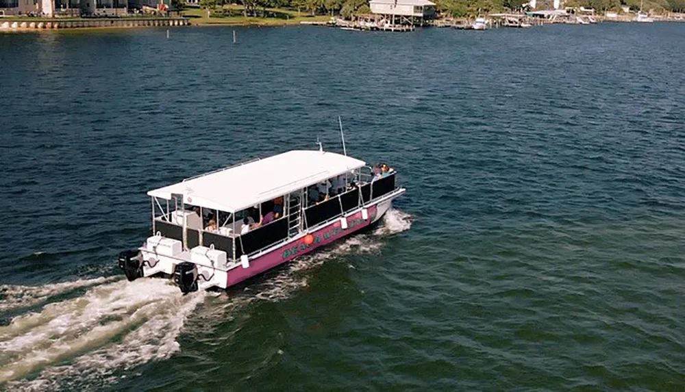A pink and white boat is cruising through the water with passengers on board