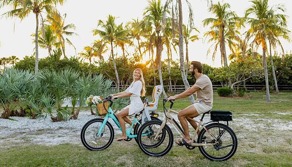 A couple enjoy a bike ride together through a scenic area with palm trees at sunset