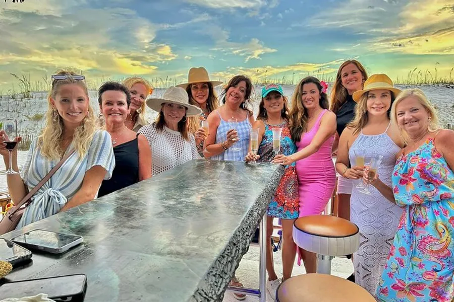 A group of women are enjoying a social gathering outdoors with drinks, near a bar with a beautiful sky in the background.