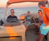 Three people are smiling and posing for a photo on a boat with a beautiful sunset over the water in the background