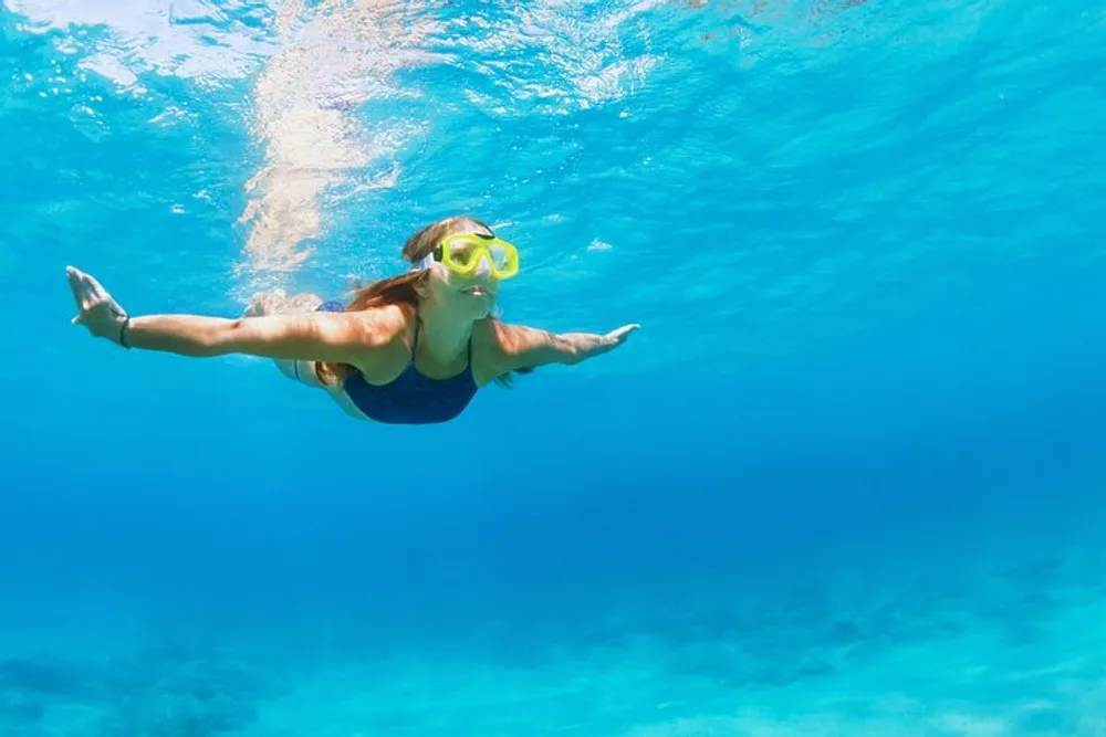 A person is snorkeling underwater in a clear blue ocean