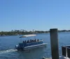 A blue and white pontoon boat named Emil Chaser is docked at a marina beside a larger vessel with clear skies in the background