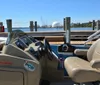 A blue and white pontoon boat named Emil Chaser is docked at a marina beside a larger vessel with clear skies in the background