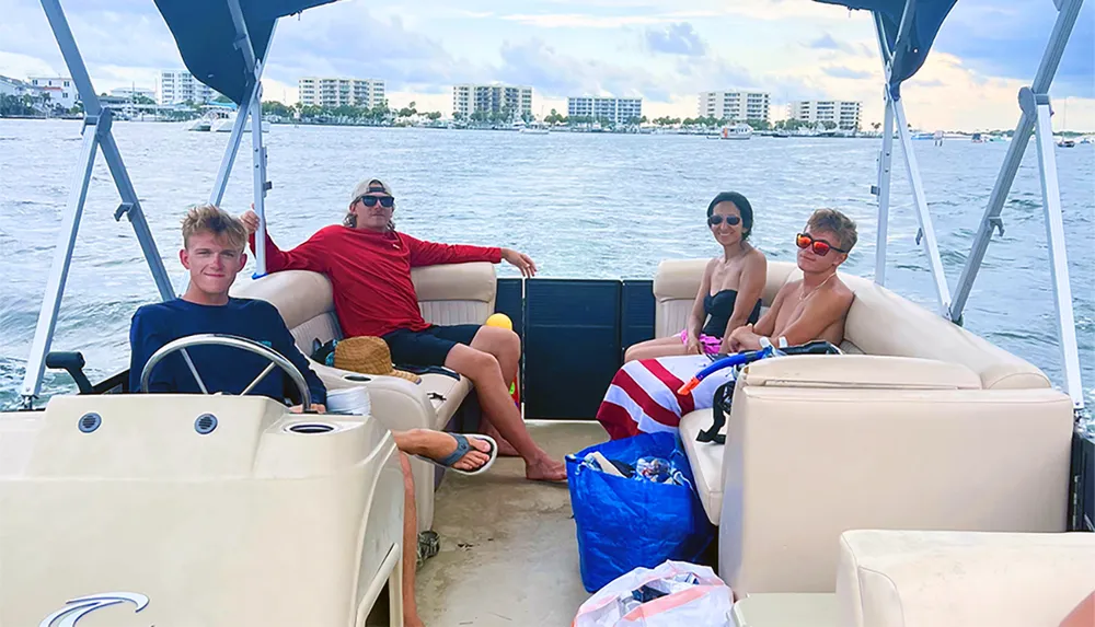 Four people are enjoying a boat ride together with coastal buildings in the background