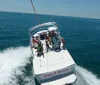 Two people are parasailing above the ocean towed by a boat that is moving swiftly across the water