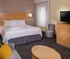 The image shows a neatly arranged modern hotel room with a large bed a television a sitting area and a minimalist decor