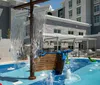 A childrens splash pad features playful water streams and a small ship structure set against the backdrop of a modern apartment building