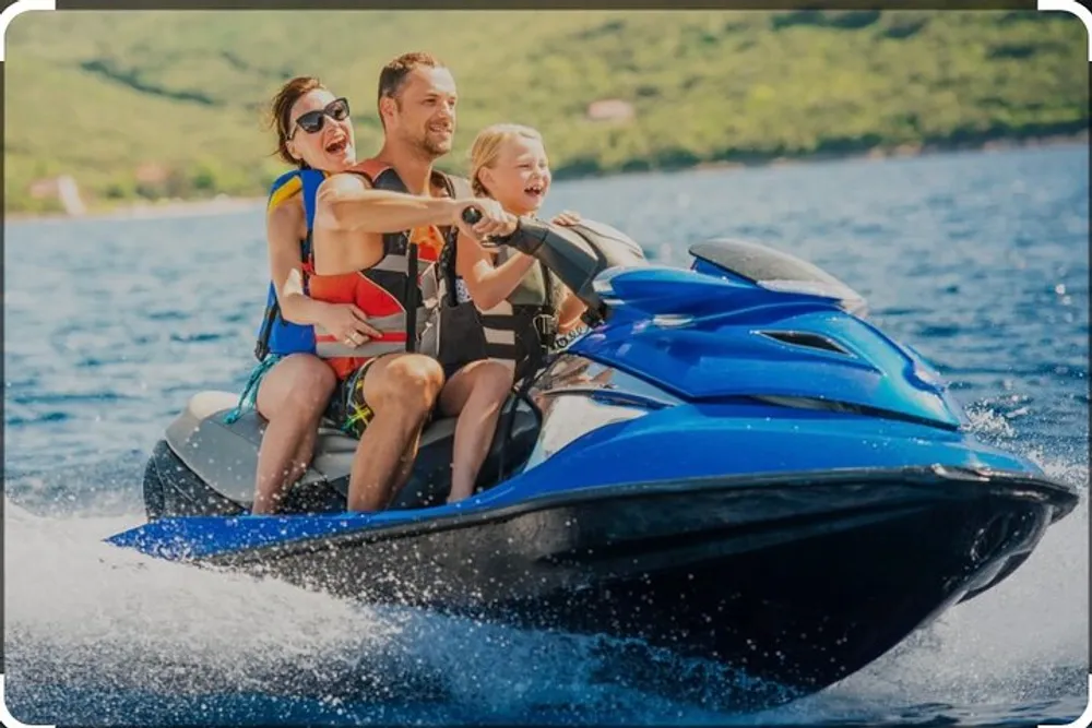 Three people two adults and a child are joyfully riding a blue jet ski on a sunny day