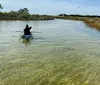 A person is paddling a transparent kayak over clear water offering a view of the underwater environment