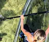 A person is paddling a transparent kayak over clear water offering a view of the underwater environment