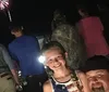 A girl smiles for the camera with a man beside her while other people watch fireworks at night