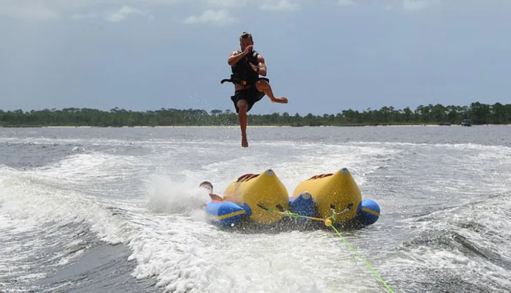 A person is airborne above an inflatable tube on a water body appearing to have been ejected during a water sport activity
