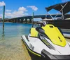 A person is energetically posing with a peace sign while seated on a green and white Yamaha WaveRunner on the water