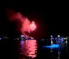 A vibrant fireworks display reflects on a body of water at night
