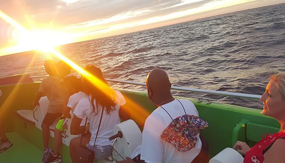 Passengers on a boat are enjoying a vibrant sunset over the ocean