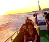 Passengers are enjoying a sunset boat ride on the ocean with a warm glow from the setting sun reflecting on the water