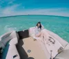 A person is lounging on a boat surrounded by clear blue water under a bright sky
