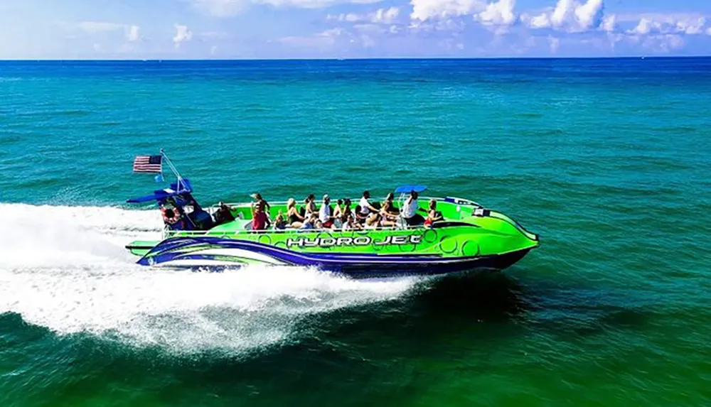 A group of passengers is enjoying a ride on a vibrant green speedboat named Hydrojet as it speeds across blue ocean waters under a clear sky