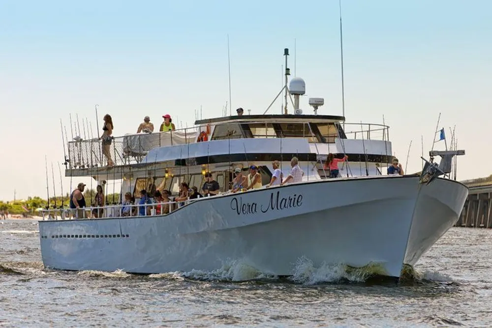 A group of people are aboard a multi-level boat named Vera Marie enjoying their time on what appears to be a leisure cruise