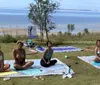Two people are lying on yoga mats in a relaxation pose seemingly engaged in an outdoor yoga practice
