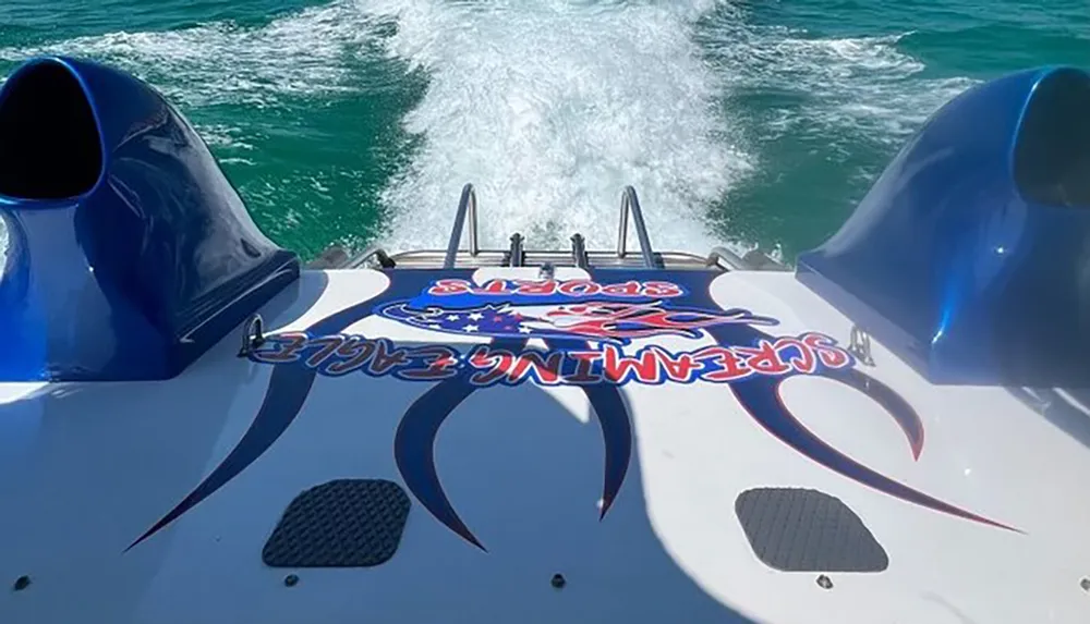 The image shows the rear deck of a high-speed boat with powerful engines capturing the wake of turbulent water as the vessel moves swiftly through the sea