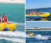 A group of people wearing life jackets are enjoying a ride on a yellow banana boat being pulled by a motorboat on a blue sea