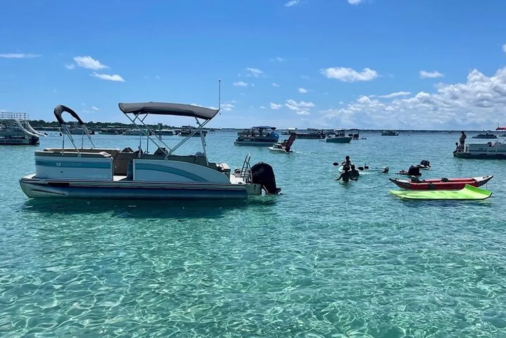 The image shows a sunny day with people enjoying clear turquoise waters surrounded by various boats and a kayak indicative of leisure activities at a tropical location