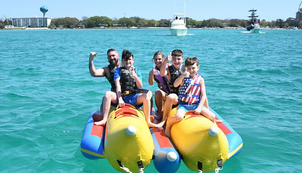 A group of people possibly a family is enjoying themselves on a colorful banana boat ride on a clear sunny day at the sea