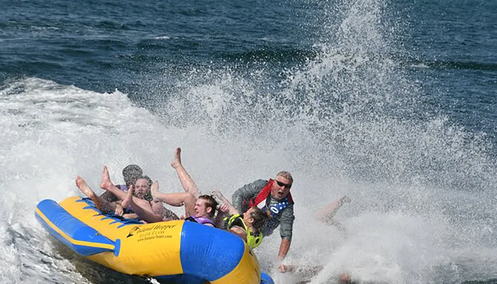 A group of people are experiencing a thrilling and splash-filled ride on a yellow inflatable banana boat being towed over choppy waters