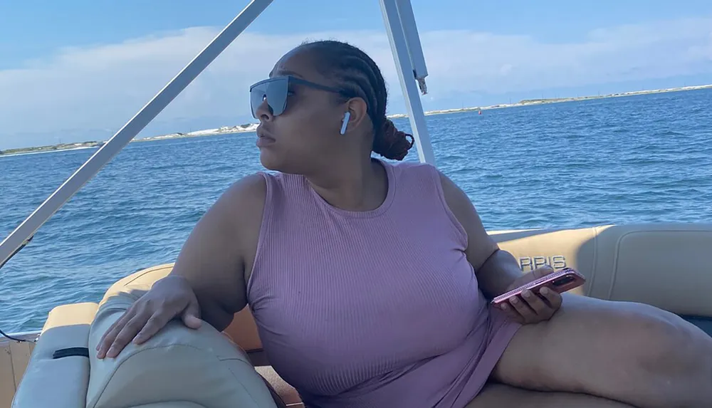 A person is relaxing on a boat with a smartphone in hand looking out over the water