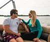 A man and a woman are enjoying a moment together on a boat chatting and smiling with a serene water backdrop