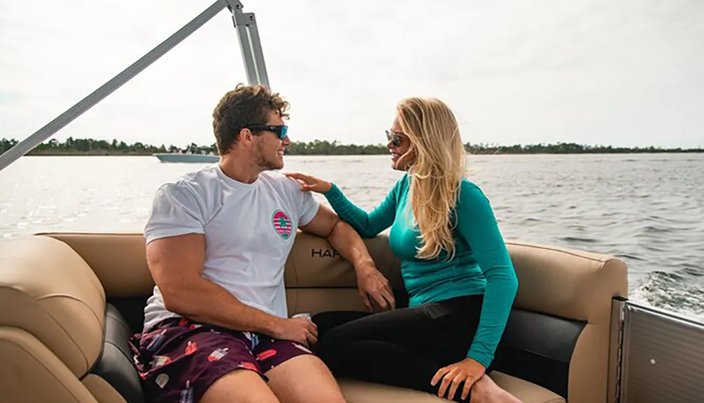 A man and a woman are enjoying a moment together on a boat chatting and smiling with a serene water backdrop