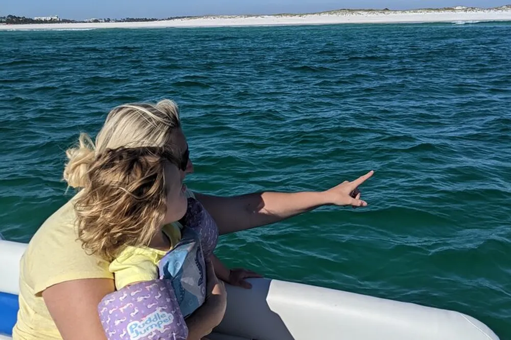 A person is pointing towards the water while looking out from the side of a boat