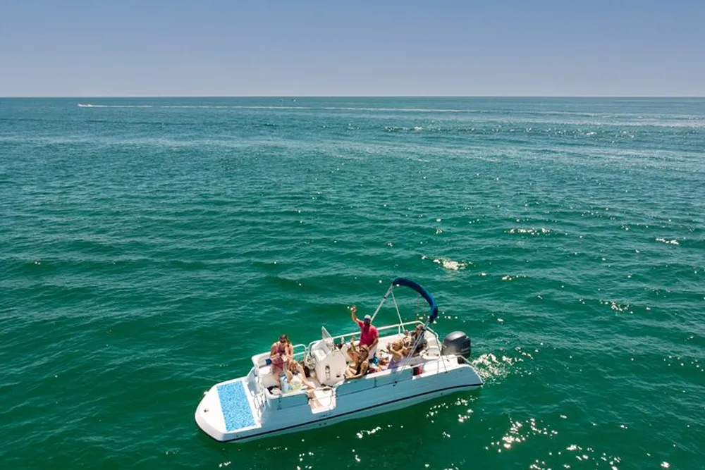 A group of people are enjoying a sunny day on a small boat in the expansive blue ocean