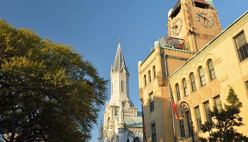 The image features a streetscape showing a historic clock tower and a white church spire against a clear blue sky flanked by green trees