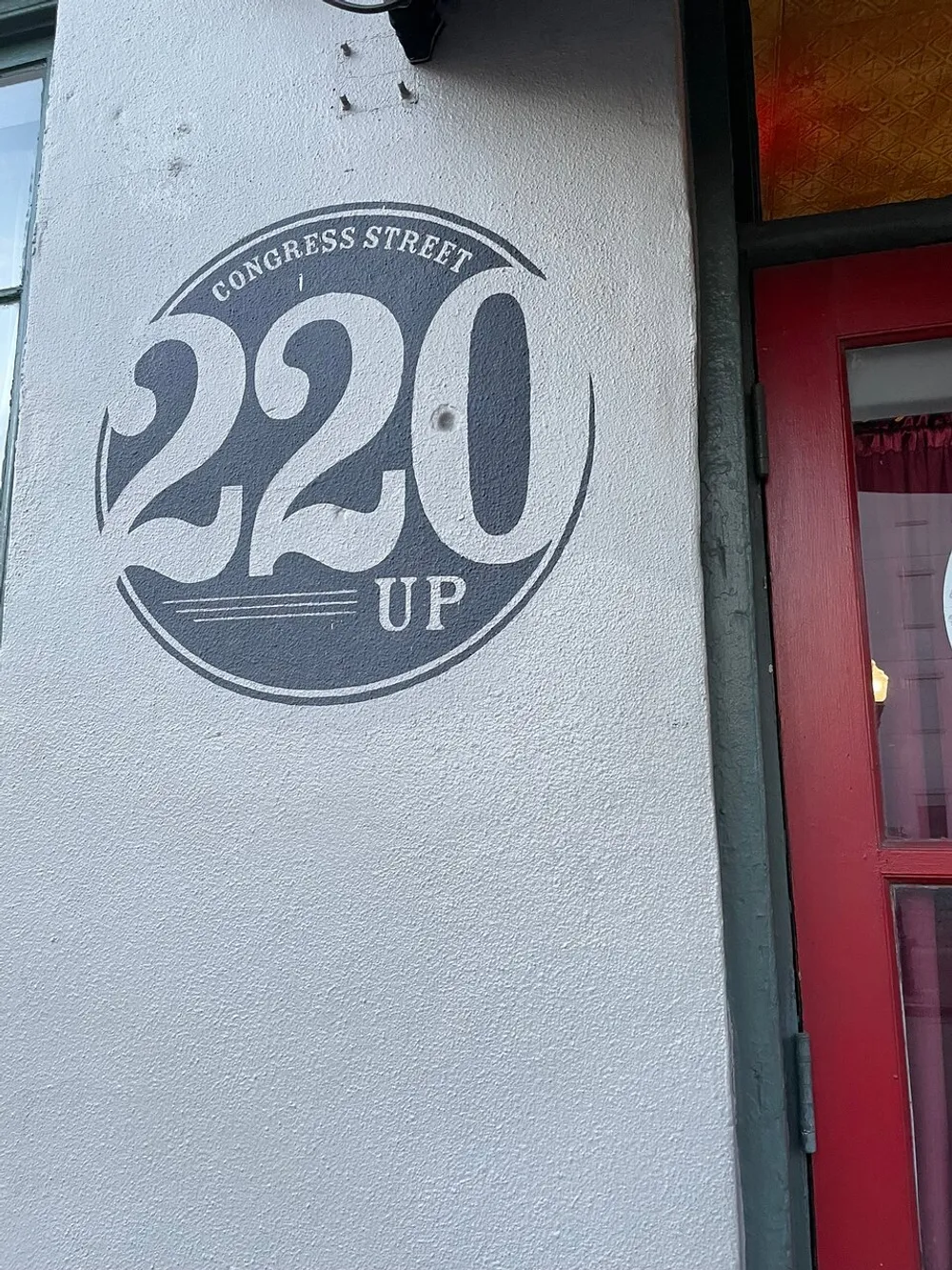 The image shows a stylized sign on a buildings exterior wall featuring the address 220 CONGRESS STREET UP